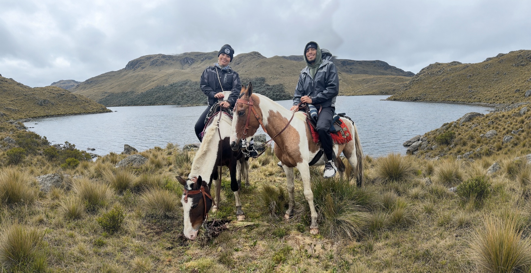 Raisa and Brian on horseback beside a lake in the Ecuadorian highlands